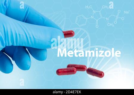 Hand mit blauem Latexhandschuh hält eine Kapsel Metamizol über einem Hintergrund mit seiner chemischen Zusammensetzung. Ist ein Schmerzmittel, Krämpfen Reliever und Fieber r Stockfoto