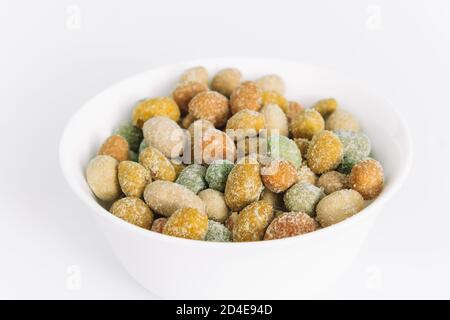 Gesalzene Erdnüsse mit Glasur in einer Keramikschale auf weißem Hintergrund bedeckt. Köstliche Vorspeise. Ein Snack auf dem Weg. Nahaufnahme. Speicherplatz kopieren. Stockfoto