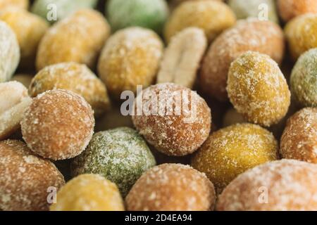 Hintergrund für das Essen. Makro. Gesalzene Erdnüsse mit mehrfarbiger Glasur bedeckt. Köstliche Vorspeise. Ein Snack auf dem Weg. Selektiver Fokus. Speicherplatz kopieren. Stockfoto