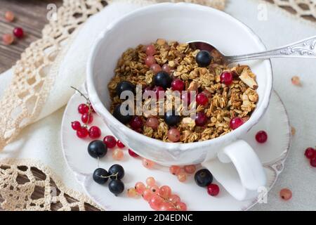 Hausgemachtes leckeres gesundes Müsli mit Nüssen, Samen, Honig und frischen Beeren in einem Keramikbecher Stockfoto