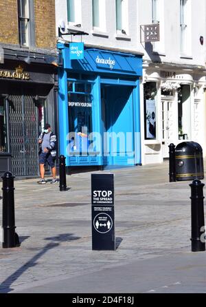 Ein Mann mit einer schützenden Gesichtsmaske geht an einem Stop the Ausbreitung von Coronavirus sozialen distanzierenden Straßenschild in Covent Garden, London 2020 vorbei Stockfoto