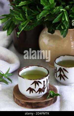 Minztee in einem Vintage chinesischen Tee-Set und ein Minzbouquet in einer Kanne. Rustikaler Stil. Stockfoto