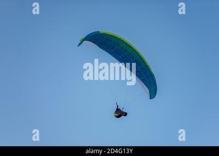 Paragleiter mit bunten Fallschirmen fliegen hoch in den klaren blauen Himmel über steile Klippen. Fallschirmspringen, Nebennierenentzündung, Liebe zur Höhe, Risiko, Freiheit Stockfoto