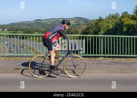 Männlicher Radfahrer, der Cannondale Kohlefaser Sport Rennrad auf Landstraße überquert Autobahnbrücke im ländlichen Lancashire, Großbritannien Stockfoto