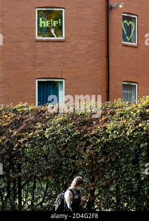 Nottingham, Nottinghamshire, Großbritannien. Oktober 2020. Eine Frau geht an einem Hilfsschild vorbei, das im Fenster einer Studentenwohnheim hängt, nachdem angekündigt wurde, dass Nottingham die höchste Covid-19-Infektionsrate in Großbritannien hat. Credit Darren Staples/Alamy Live News. Stockfoto