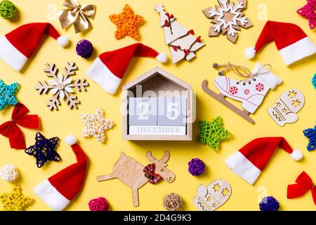 Blick von oben auf die Holz- Kalender mit Weihnachtsschmuck und Santa Hüte auf gelben Hintergrund. Die Zwanzig 5. Dezember. Happy Holiday Konzept. Stockfoto