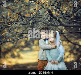 Junge und Mädchen verkleidet als Braut und Bräutigam stehen unter Ein Apfelbaum Stockfoto