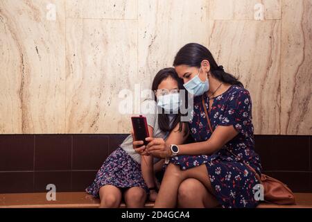 Hispanische Mutter und ihre Tochter tragen Gesichtsmasken und nehmen Ein Selfie Stockfoto