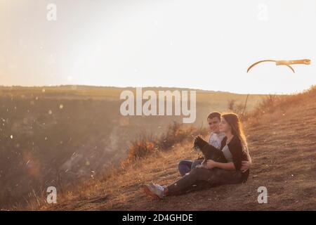 Sitzen auf einem Canyon, Blick auf Gleitschirme fliegen in den Himmel bei Sonnenuntergang. Reise mit Haustieren. Junge Familie mit einem schnauzer Hund reisen. Moldawien, Old Orhey Stockfoto