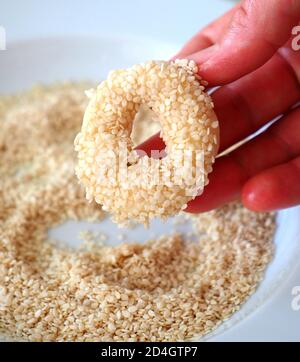 Nahaufnahme Sesamsamen, die auf den Teig geklebt sind, winzige Bagels mit Sesamsamen, Stockfoto