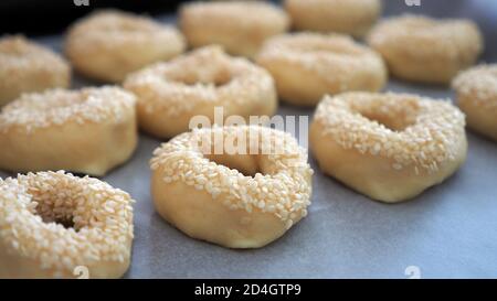 Nahaufnahme Sesamsamen, die auf den Teig geklebt sind, winzige Bagels mit Sesamsamen, Stockfoto