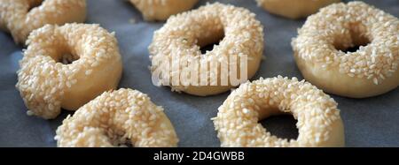 Nahaufnahme Sesamsamen, die auf den Teig geklebt sind, winzige Bagels mit Sesamsamen, Stockfoto
