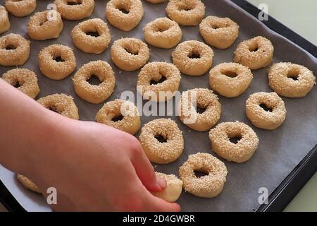 Nahaufnahme Sesamsamen, die auf den Teig geklebt sind, winzige Bagels mit Sesamsamen, Stockfoto