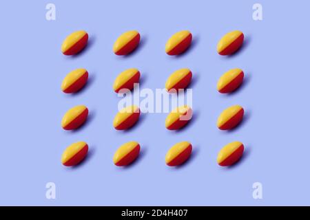 Rote und gelbe Kapsel Pharmazeutische Medizin Tablette auf blauem Hintergrund, Medizin kreative Konzepte. Minimalistischer Stil mit buntem Papierhintergrund.Tren Stockfoto