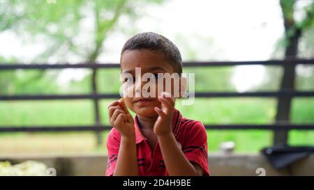 Ein süßer indischer Junge. Porträt eines lächelnden Kleinkindes, isoliert, grün verschwommener Hintergrund. Stockfoto