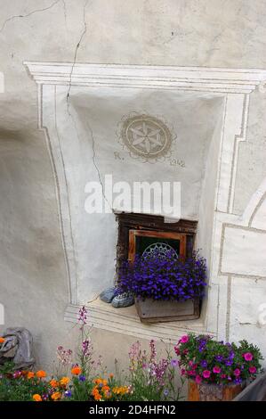 Kleine Fenster und Blumen im alten Dorf Guarda, Gemeinde Scuol, Engadintal, Kanton Graubünden, Schweiz, Europa Stockfoto