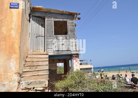 Famagusta, Nordzypern. Okt. 2020. Dieses Bild vom 8. Oktober 2020 zeigt ein verfallendes Gebäude im verlassenen Badeort Varosha in der türkischen Republik Nordzypern (TRNC), Mit Menschen in der Nähe am Strand, nachdem die Öffentlichkeit zum ersten Mal seit 46 Jahren Zugang zu diesem eingezäunten Gebiet von Famagusta erhalten. Varosha blieb jahrzehntelang unberührt und wurde nach dem Zypernkrieg 1974 von den türkischen Behörden abgedichtet, als seine überwiegend griechisch-zypriotischen Einwohner flohen und die Insel geteilt wurde. (Fotos von Selim KUMBARACI / Pasedembo / Alamy Live News Stockfoto