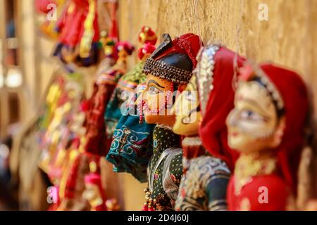 Bunte menschliche Gesicht geformt Puppets tragen bunte Kleidung hängend gegen Die Mauer in Rajasthan Indien am 21. Februar 2018 Stockfoto