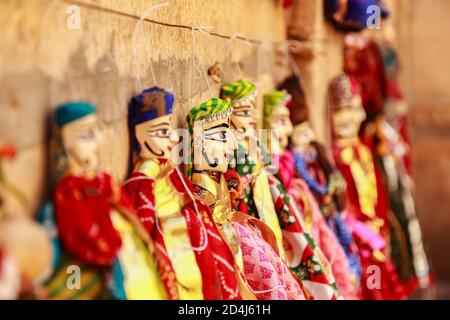 Bunte menschliche Gesicht geformt Puppets tragen bunte Kleidung hängend gegen Die Mauer in Rajasthan Indien am 21. Februar 2018 Stockfoto