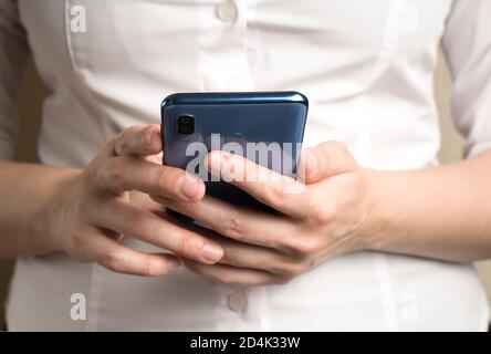 Eine Frau in einem weißen Hemd hält ein Telefon. Stockfoto