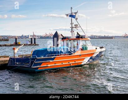 Ölablaufboot in der Nähe der Seabusstation, North Vancouver, BC, Kanada. Hafen, große Hafenkrane, Tanker und Stadt im Hintergrund sichtbar. Stockfoto