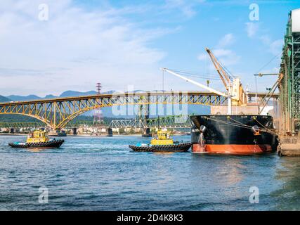 VANCOUVER, BC / KANADA - 29. MAI 2020 - zwei Schlepper nähern sich einem angedockten Tanker an einem Terminal vom Hafen von Vancouver. Stockfoto