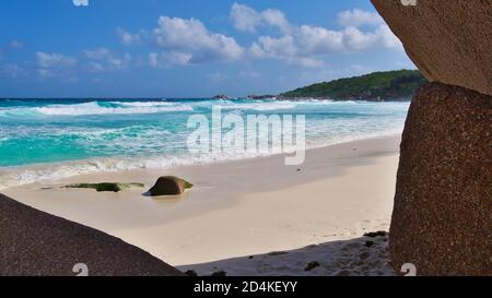 Wunderschöner tropischer Strand Grand Anse mit türkisfarbenem Wasser und starken Wellen im Süden der Insel La Digue, Seychellen, eingerahmt von Granitfelsen. Stockfoto