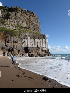 Frau läuft, um die ankommende Brandung in Fall Bay zu vermeiden -ein geschützter Sandstrand bei Ebbe von steilen umgeben Kalksteinfelsen und wunderschöne Landschaft Stockfoto