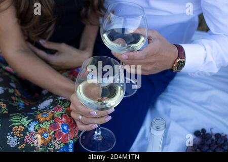 Zwei Hände -Männer und Frauen halten Champagner Gläser auf weiße Decke. Picknick. Stockfoto