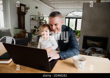 Vater und Tochter lachen über lustige Videos auf Laptop-Bonding und verbringen gemeinsam Zeit in der Familie. Stockfoto