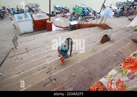 Ein Junge klettert die Treppe des Tempels am Ganges Fluss hinauf. In Varanas Stockfoto