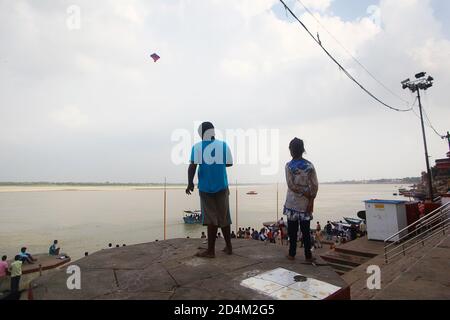 Kinder fliegen einen Drachen am Ganges Fluss in Varanasi, Indien Stockfoto