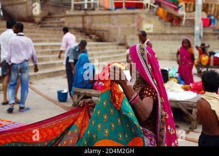 Eine Frau verkauft traditionelle Kleidung am Ganges Fluss. In Varanasi, In Stockfoto