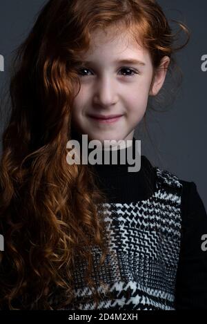 Portrait von jungen Mädchen mit lockigen roten Haaren und kariert Kleid Stockfoto