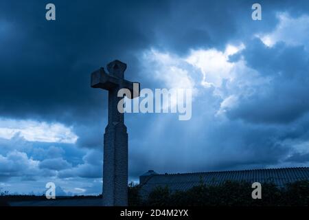 christliches Kreuz gegen dramatischen düsteren dunklen Himmel, mit Sonnenstrahlen kommen durch düstere Wolken der großen Flut, Konzept des letzten Gerichts oder Apokalypsen Stockfoto