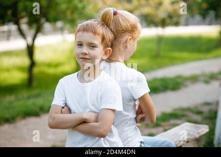 Die Kinder vergehen sich gegenseitig im Park auf der Bank. Stockfoto