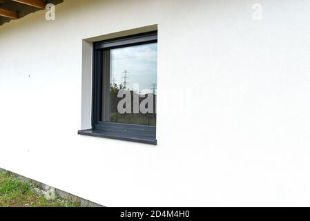 Eine neu aufgebrachte Schicht aus weißem Silikonputz an der Wand des Hauses, sichtbares Fenster in anthrazit. Stockfoto