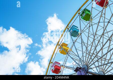 Mehrfarbige Riesenrad-Kabinen vor einem blauen Himmel mit Wolken Stockfoto