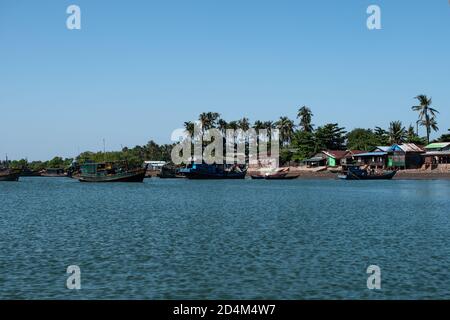 Mehrere traditionelle Holzboote in einem Fluss und Häuser am Ufer des Fischerdorfes Chaung Thar, Irrawaddy, West-Myanmar Stockfoto