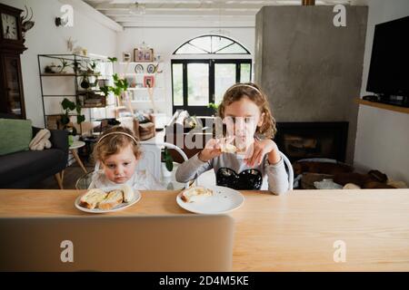 Zwei Töchter essen lecker Frühstück am Tisch in der modernen Küche. Stockfoto