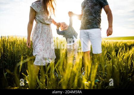 Glückliche Familie im leuchtend grünen Gras bei Sonnenuntergang. Stockfoto