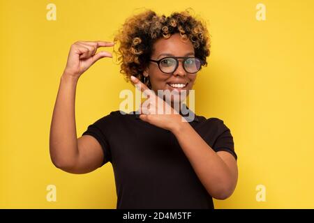 Schöne afrikanische Frau zeigt etwas kleines mit Händen Stockfoto