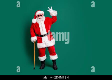 Volle Länge Körpergröße Ansicht seiner er schön attraktiv Bärtig fröhlich fröhlich froh cool funky Santa lehnt auf Stock Mit Spaß Feier zeigen Horn Stockfoto