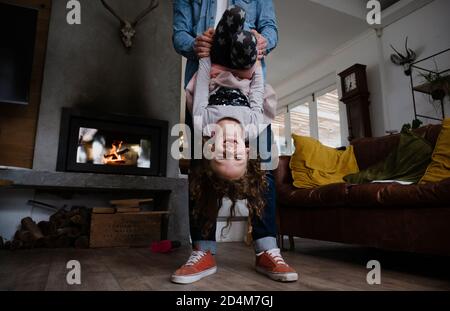 Junge kaukasische Tochter spielt mit Vater in der Lounge, auf dem Kopf Stockfoto