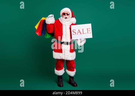 Volle Länge Körpergröße Ansicht seiner er schön Fett Fröhlich erstaunt Santa Vater mit Geschenken Geschenke Schnäppchen halten in Handverkauf Promo Card Saison Stockfoto