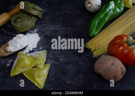 Food Hintergrund mit Spaghetti, Ravioli, Kartoffel, Pfeffer und Knoblauch auf mehligen dunklen background.Healthy hausgemachte Küche concept.Copy Raum, Ort für tex Stockfoto
