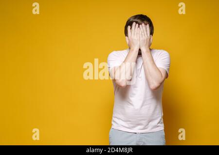 Der kaukasische Mann bedeckte sein Gesicht mit den Händen. Er ist aufgebracht, gestresst und sehr müde. Speicherplatz kopieren. Psychologisches Konzept. Stockfoto