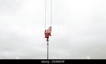 Kran roten Hebehaken gegen einen weißen bewölkten Himmel. Industrial Hintergrund Konzept. Stockfoto