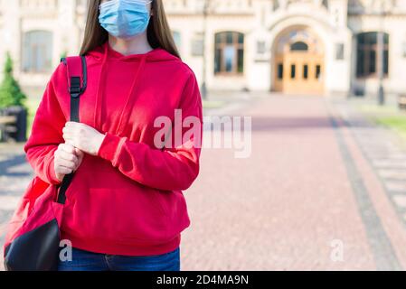 Fernlernkonzept. Cropped Nahaufnahme Foto von unglücklich traurig aufgeregt Teenager-Mädchen in beiläufigen roten Pullover mit Rucksack weg von der Universität buil Stockfoto