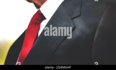 Eine schwarze Business-Anzug Jacke mit weißem Hemd und roter Krawatte, Mann Hals und Brust Nahaufnahme Textur Hintergrund mit Copy Space. Stockfoto